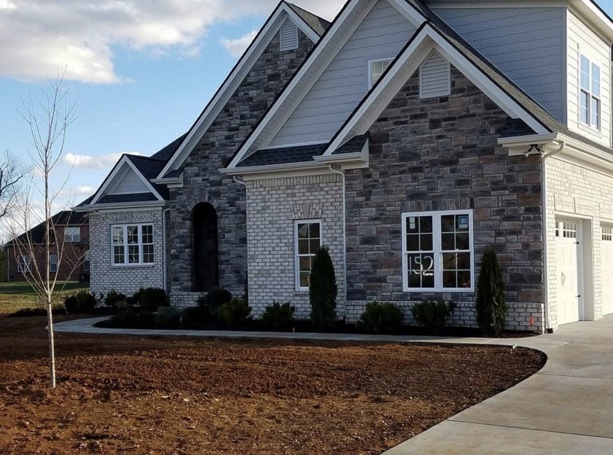 Freshly landscaped foundation beds at new construction stone and brick home