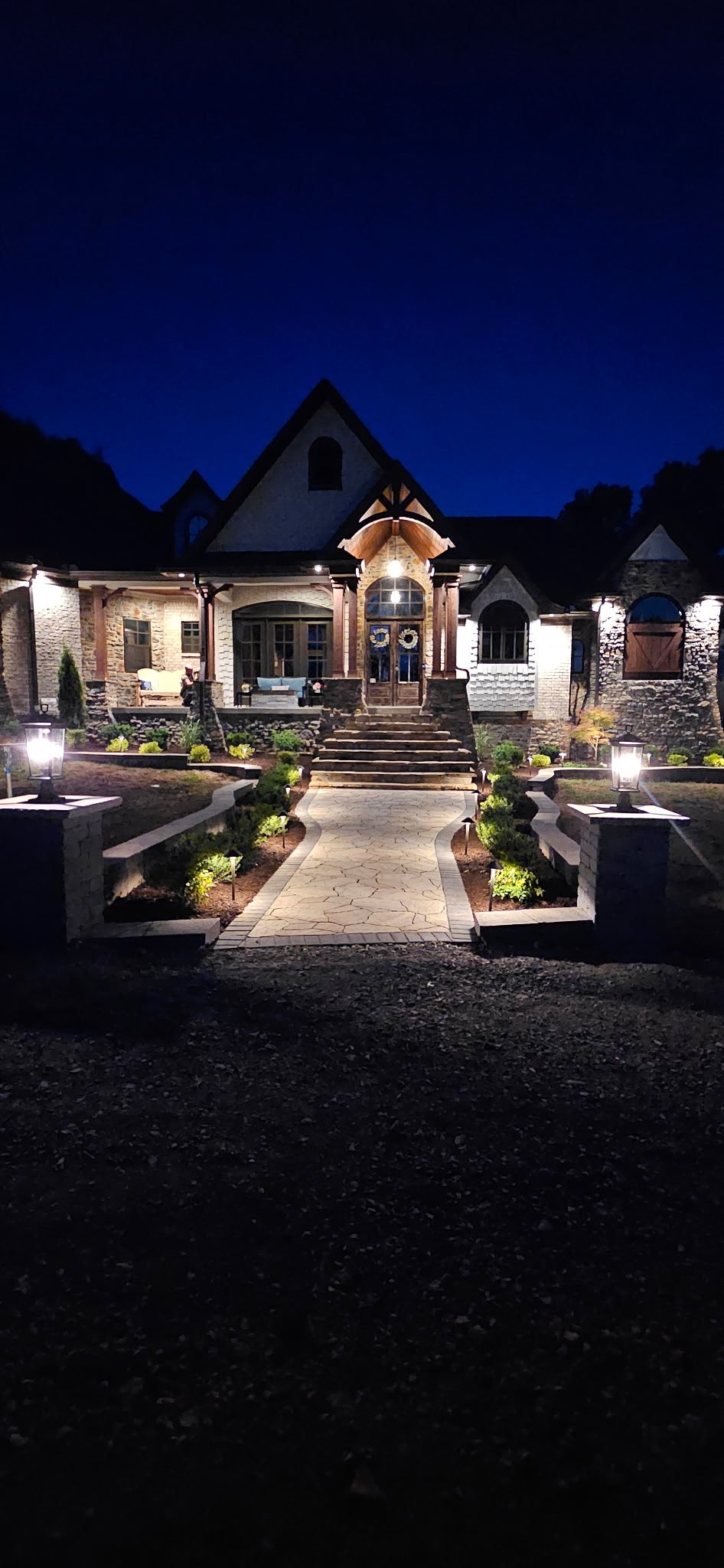 Illuminated stone walkway and steps leading to home entry at dusk