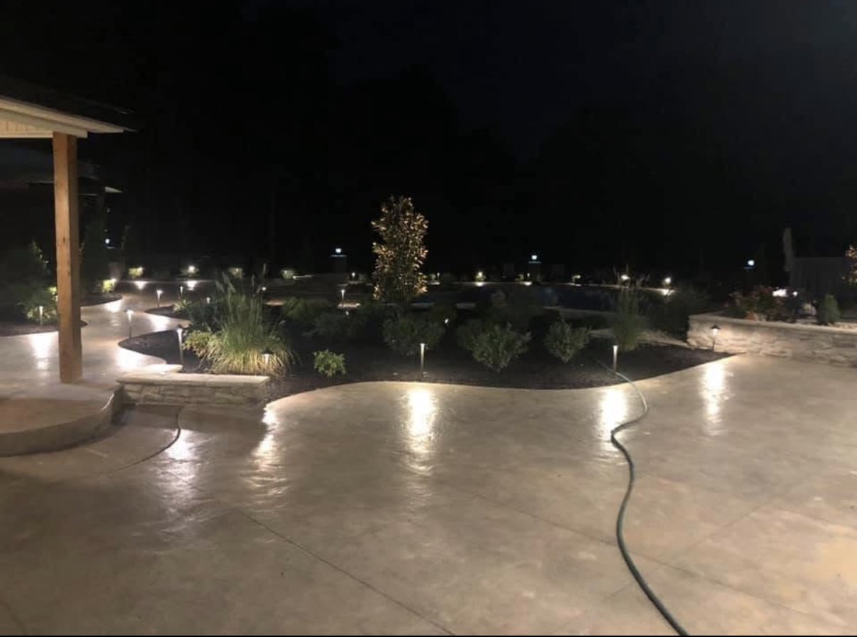 Landscape lighting around pool patio and planting beds at night