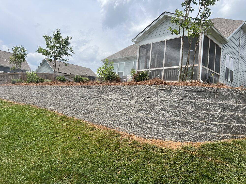 Completed retaining wall with new plantings below screened porch